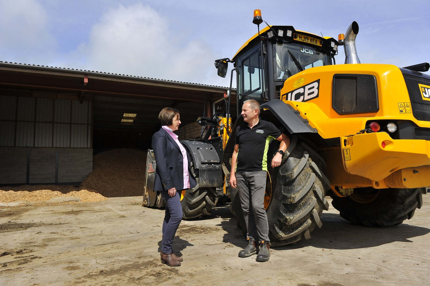 Two people talk next to farm machinery